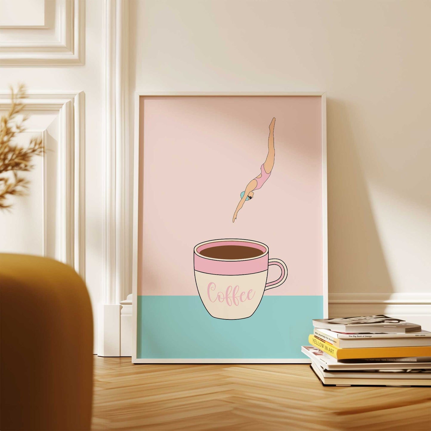 Framed artwork of a woman diving into a coffee cup with a pink and blue gradient background, displayed on a wooden surface.